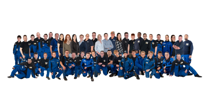 Eine große Gruppe von Menschen in blauen Arbeitsanzügen steht zusammen und lächelt in die Kamera, um Teamgeist zu zeigen.